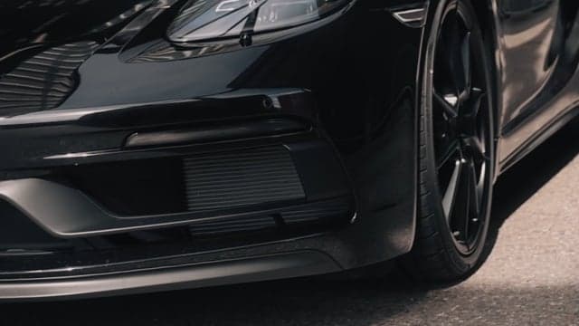 Detailaufnahme der Front eines schwarzen Sportwagens mit Frontschürze und Rad, dynamische Automotive-Aufnahme